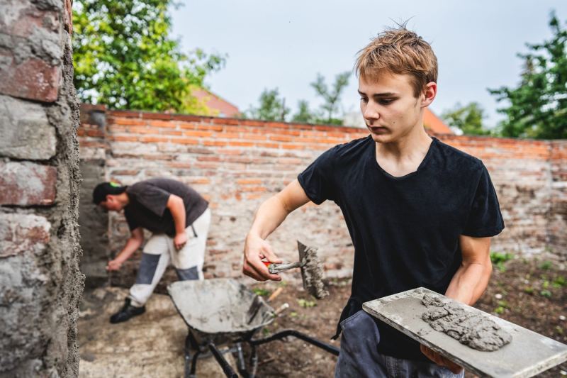 Žák oboru zedník pracuje u historické zdi